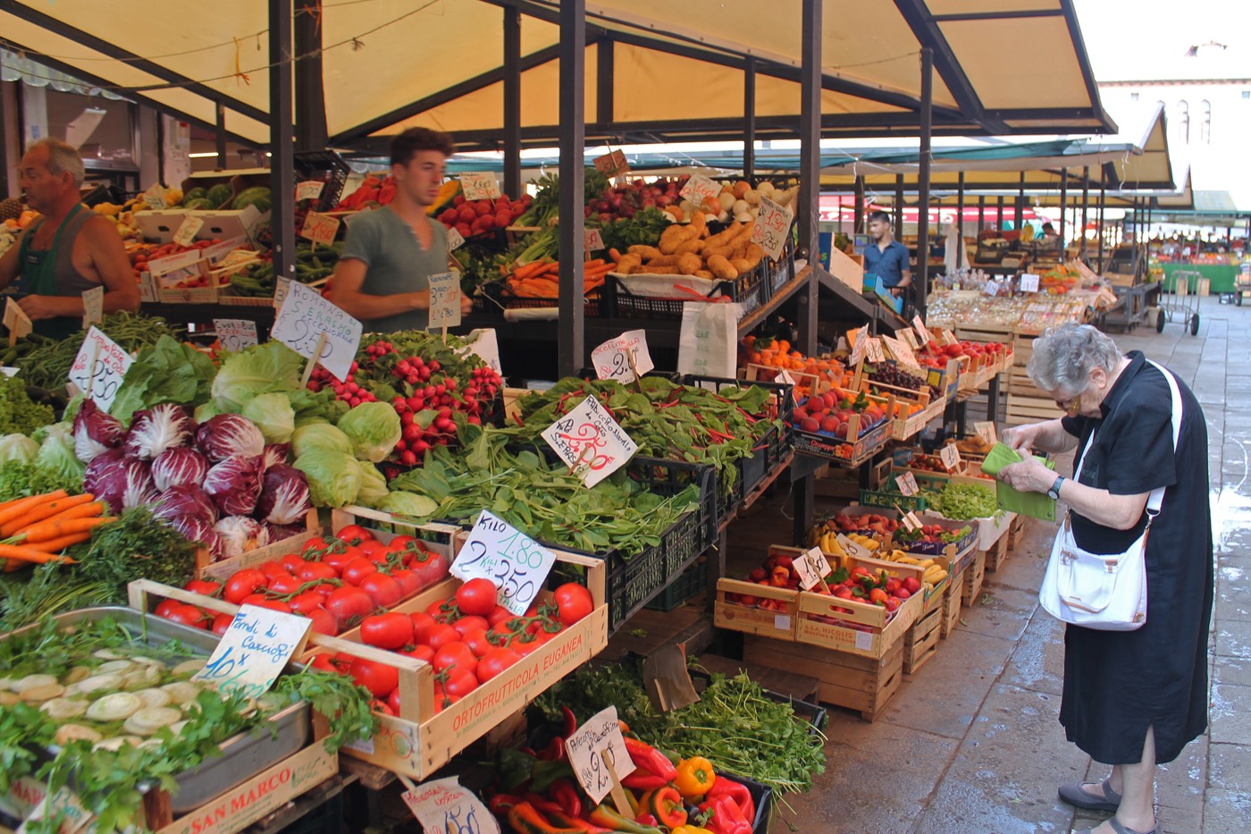 Un banco di verdure al mercato, tra venditore e clienti
